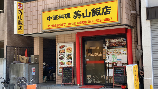中華料理美山飯店の黄色い店名看板と赤い柱の入口を正面から見た外観
